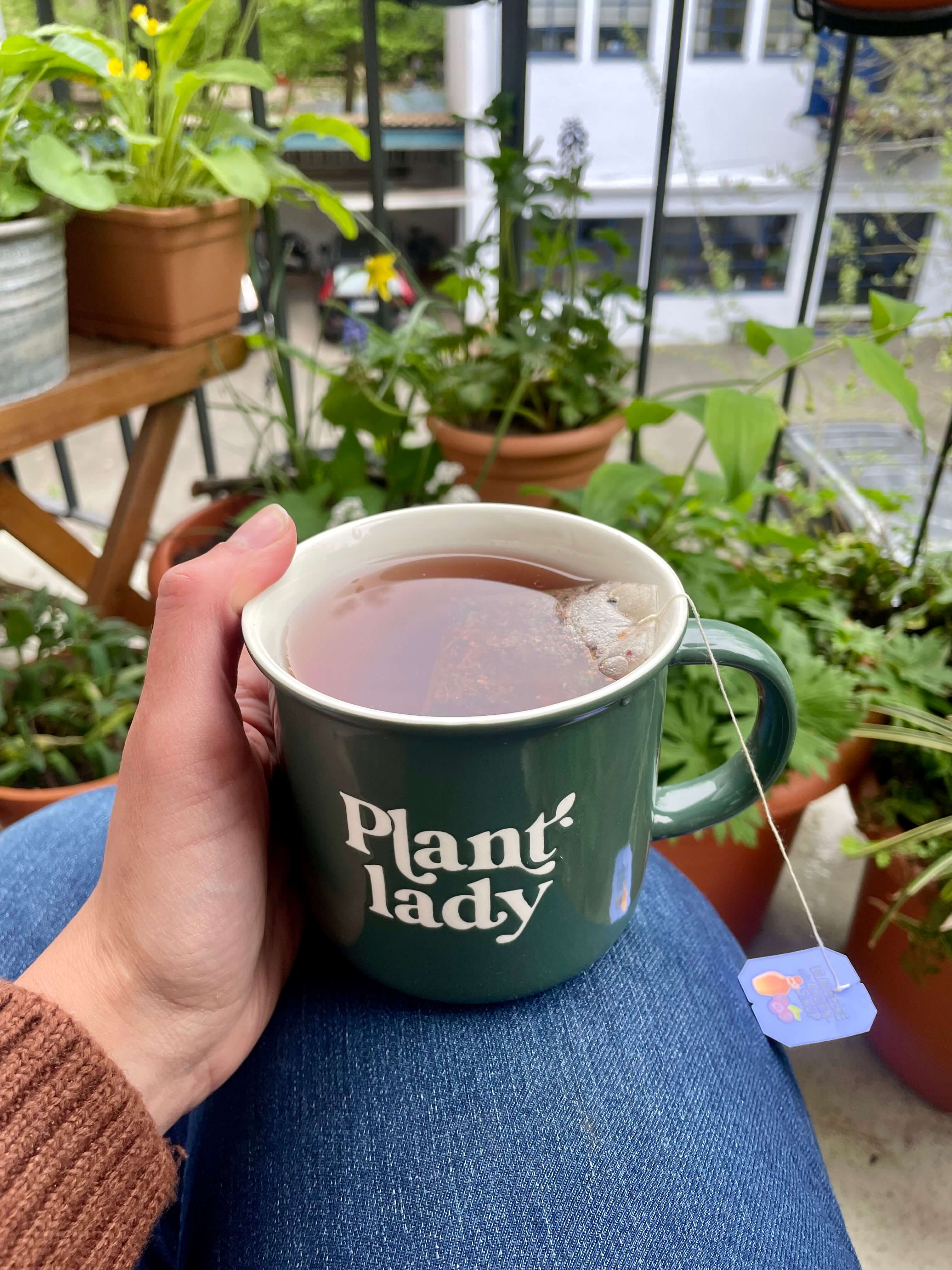 Grüne Tasse mit Aufschrift "Plant Lady" auf Balkon