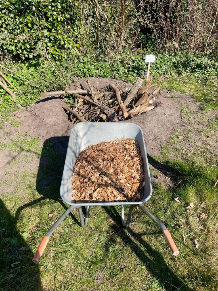 Schubkarre mit Holzhäckseln vor Käferkeller